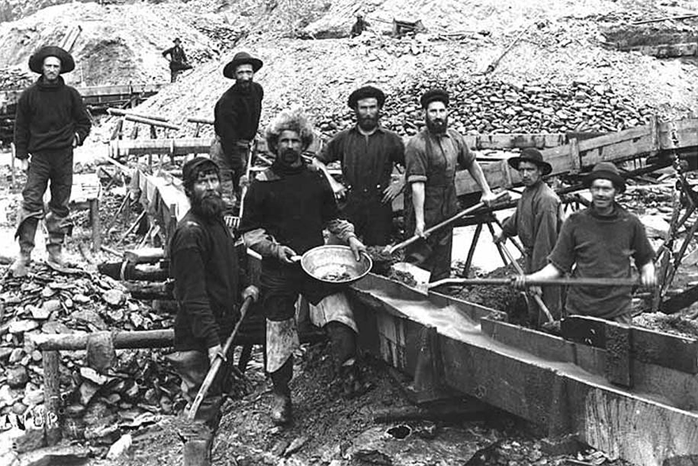 Gold mining operation showing miners using gold pan and a sluice, location unknown, ca. 1898