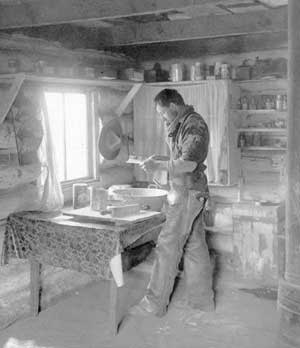Lawrence Lindsley in cabin kitchen baking bread, Lake Chelan, ca. 1910