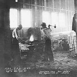 Blacksmiths at work inside a forge shop