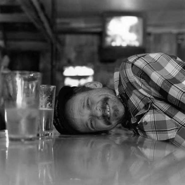 Rick Hazelton smiling and laying his head down on the bar next to beer pitcher